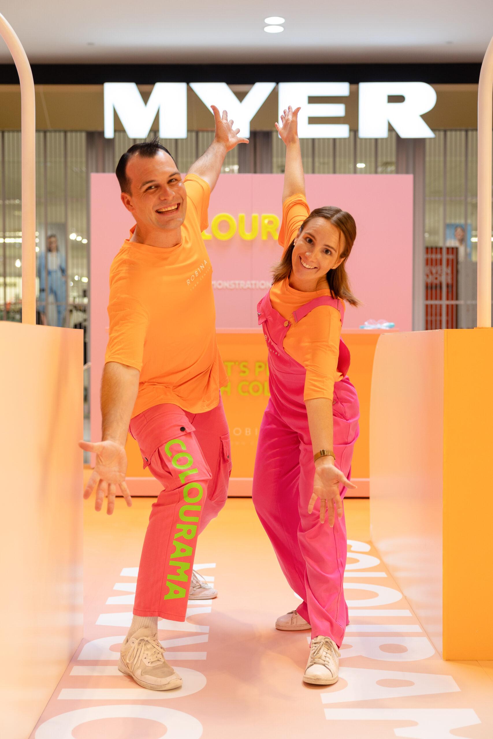 Performers Posing in Pink and Orange Uniforms in the Colourama Set.