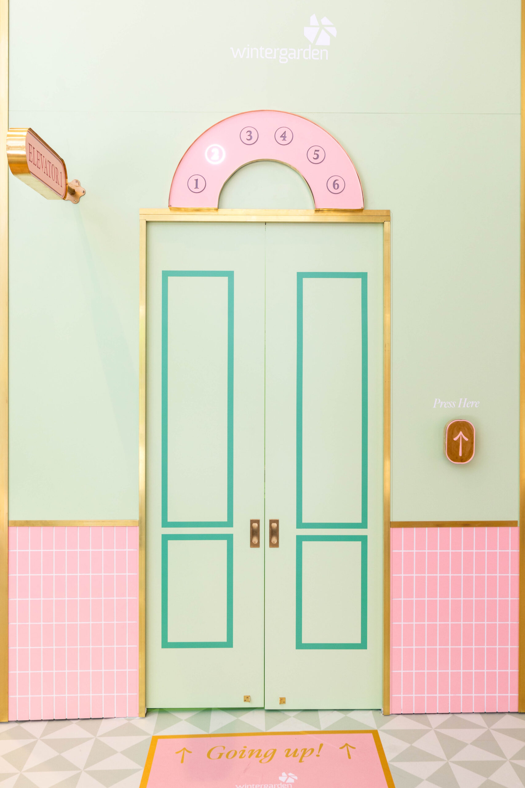 Green and Pink Elevator Door with Brass Detailing and Interactive Lights.