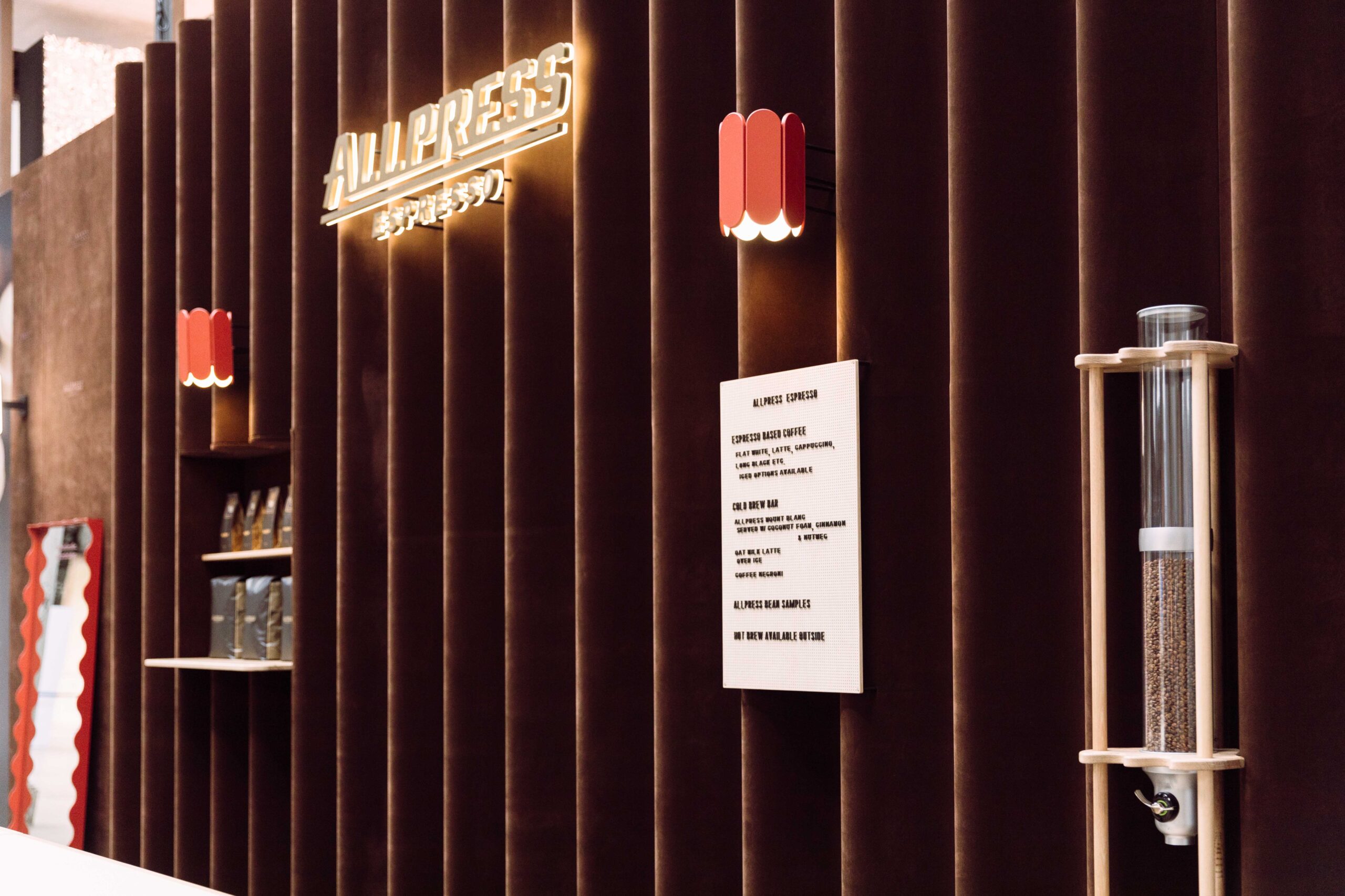 A wavy backdrop upholstered in brown velvet with a backlit sign showing the 