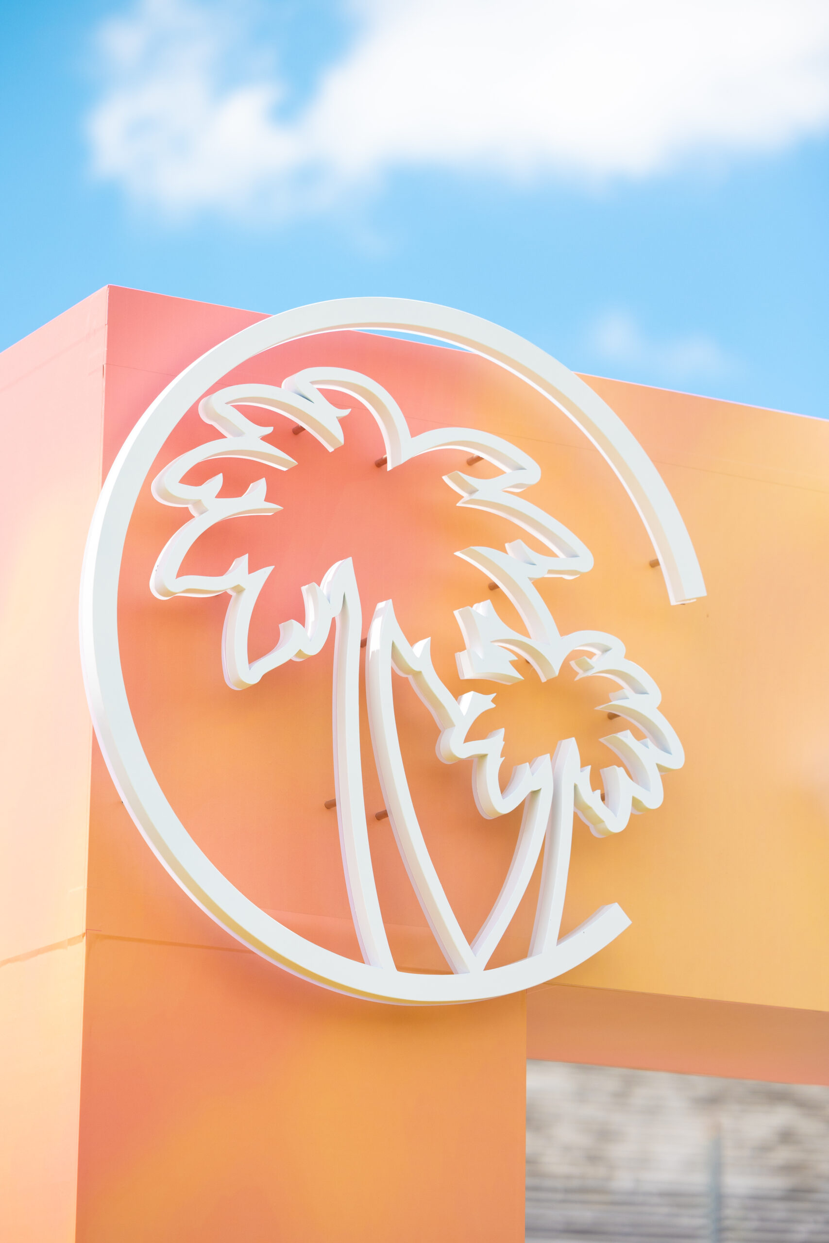 White Palm Tree Signage Against Orange Entry Arch.